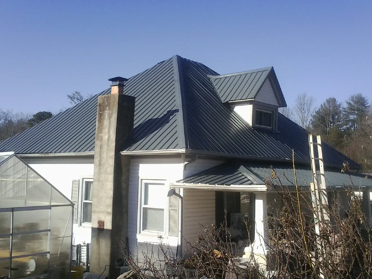Dark blue standing seam metal roof on a white farmhouse with dormer — Slate & Tile Roof Repair by Roofing Brothers in Chisago City