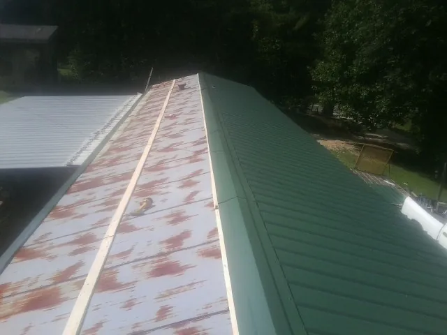 Old rusted panels beside newly installed green metal roofing — Wind Damage Roof Repair by Roofing Brothers in Chisago City
