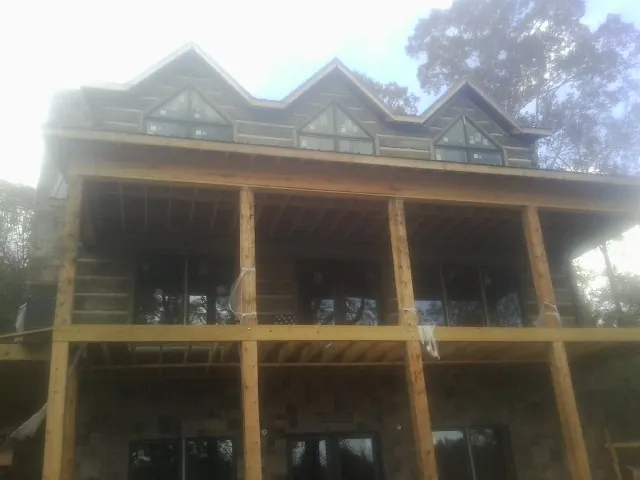 Dormers and porch framing on a large log home under construction — Roof Coating work by our crew in Chisago City
