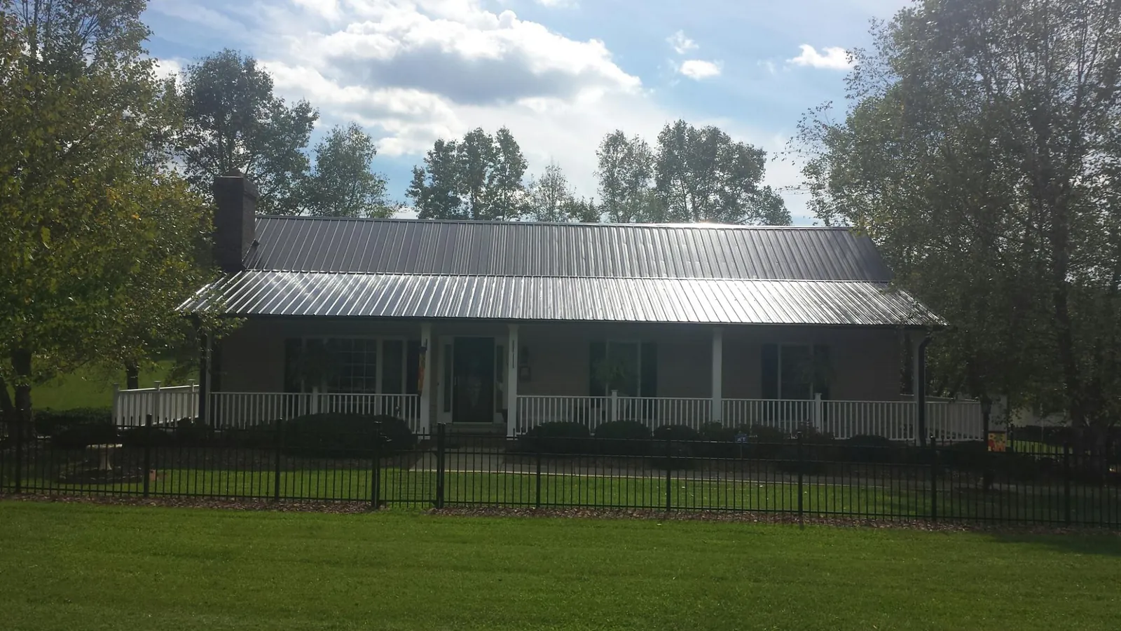Gray metal roof on a brick ranch with a full width front porch — Gutter Guard Installation work by our crew in Chisago City