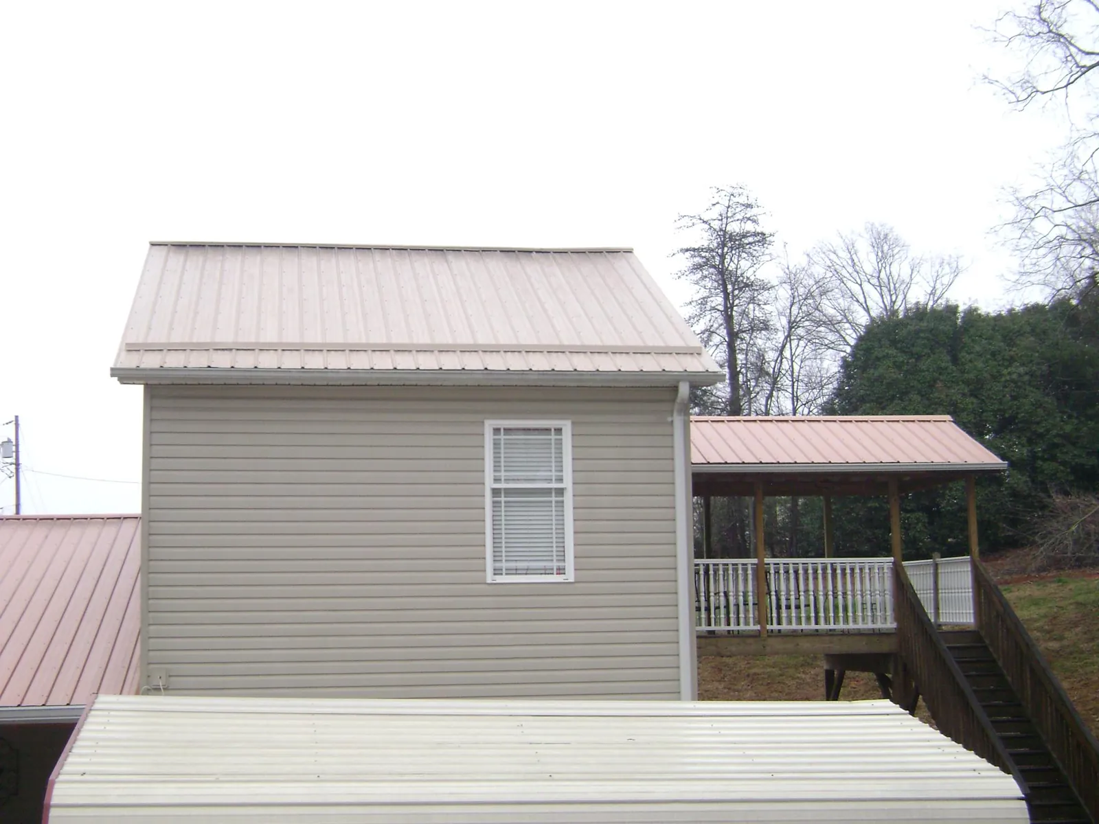 Tan metal roofs on a two story addition and attached porch, from a Roof Replacement job in Chisago City