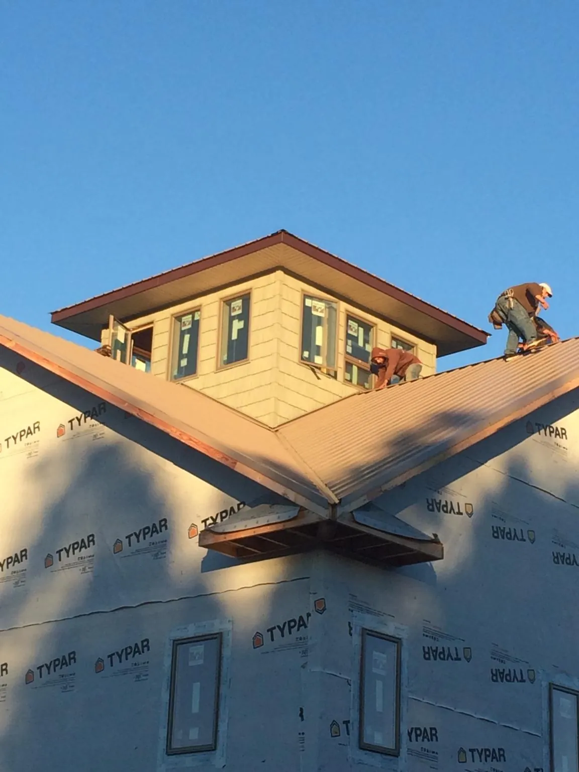Roofers working around a rooftop cupola on a new metal roof at sunset — Roof Waterproofing in Chisago City by Roofing Brothers